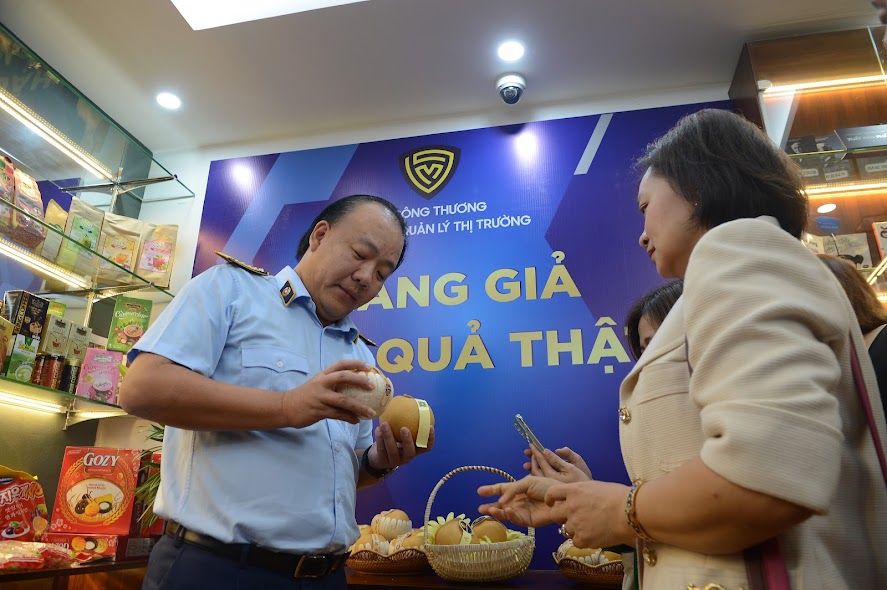 Tổng Cục trưởng Trần Hữu Linh hướng dẫn khách tham quan cách nhận diện hàng thật, hàng giả.