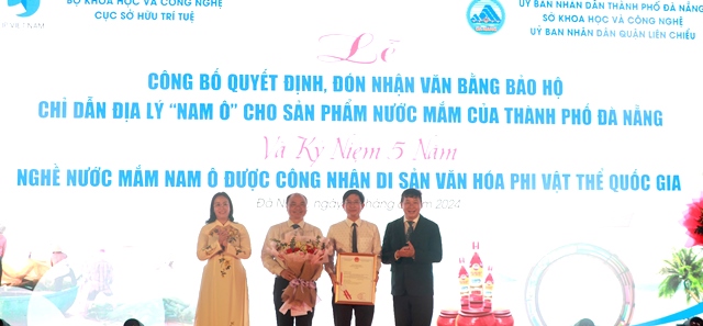 Phó Cục trưởng Cục Sở hữu trí tuệ Trần Lê Hồng (bên phải) cùng Phó Chủ tịch UBND thành phố Nguyễn Thị Anh Thi (bên trái) trao văn bằng bảo hộ và hoa chúc mừng ông Hoàng Thanh Hòa, Chủ tịch UBND quận Liên Chiểu.