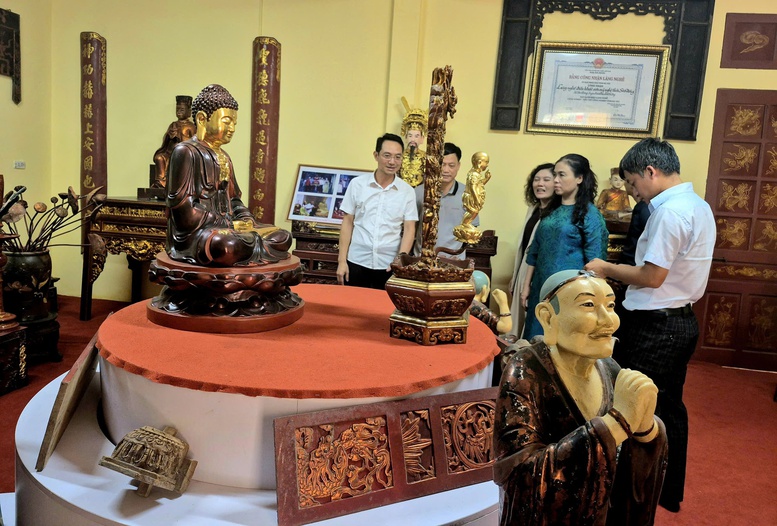 Ông Cao Văn Tâm, Phó Chủ tịch UBND xã Sơn Đồng (đeo kính) giới thiệu các sản phẩm của làng nghề Sơn Đồng. Ảnh: VGP/Thiện Tâm